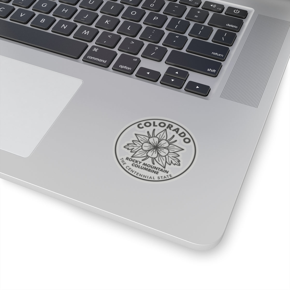 Columbine round sticker on a laptop lid, showing Colorado and state flower text