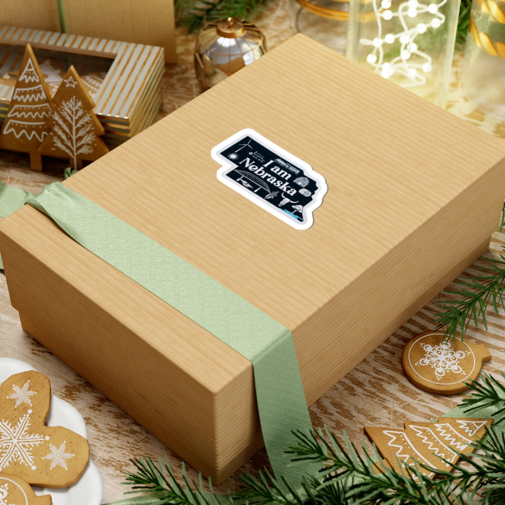 Blue 'I am Nebraska' sticker with white outline on a wrapped gift box