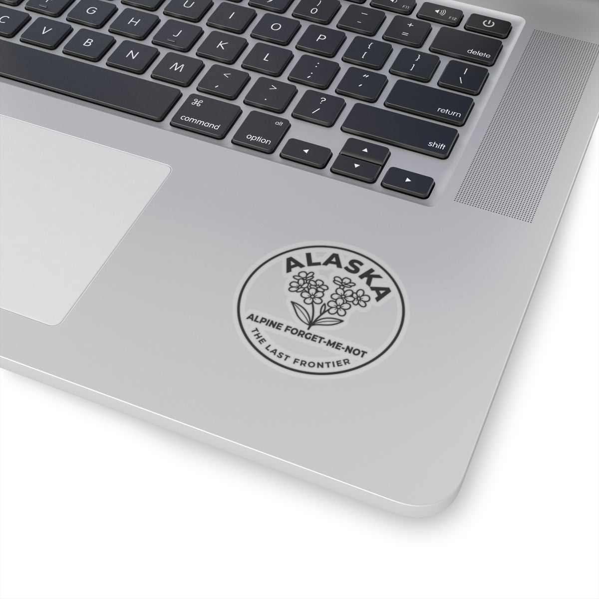 Alaska alpine forget-me-not vinyl sticker on a laptop palm rest, circular flower emblem