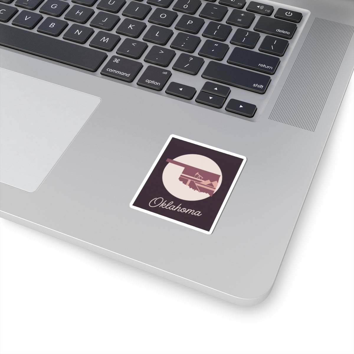Small Oklahoma state sticker on laptop: maroon square with oil derrick silhouette and Oklahoma script