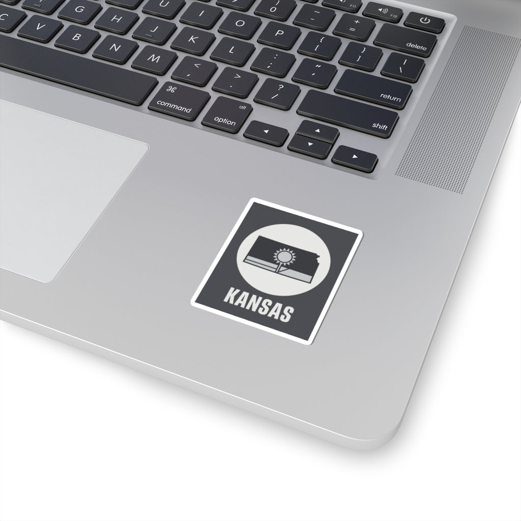 Kansas state sticker on a laptop, small dark gray square with sun and wheat field