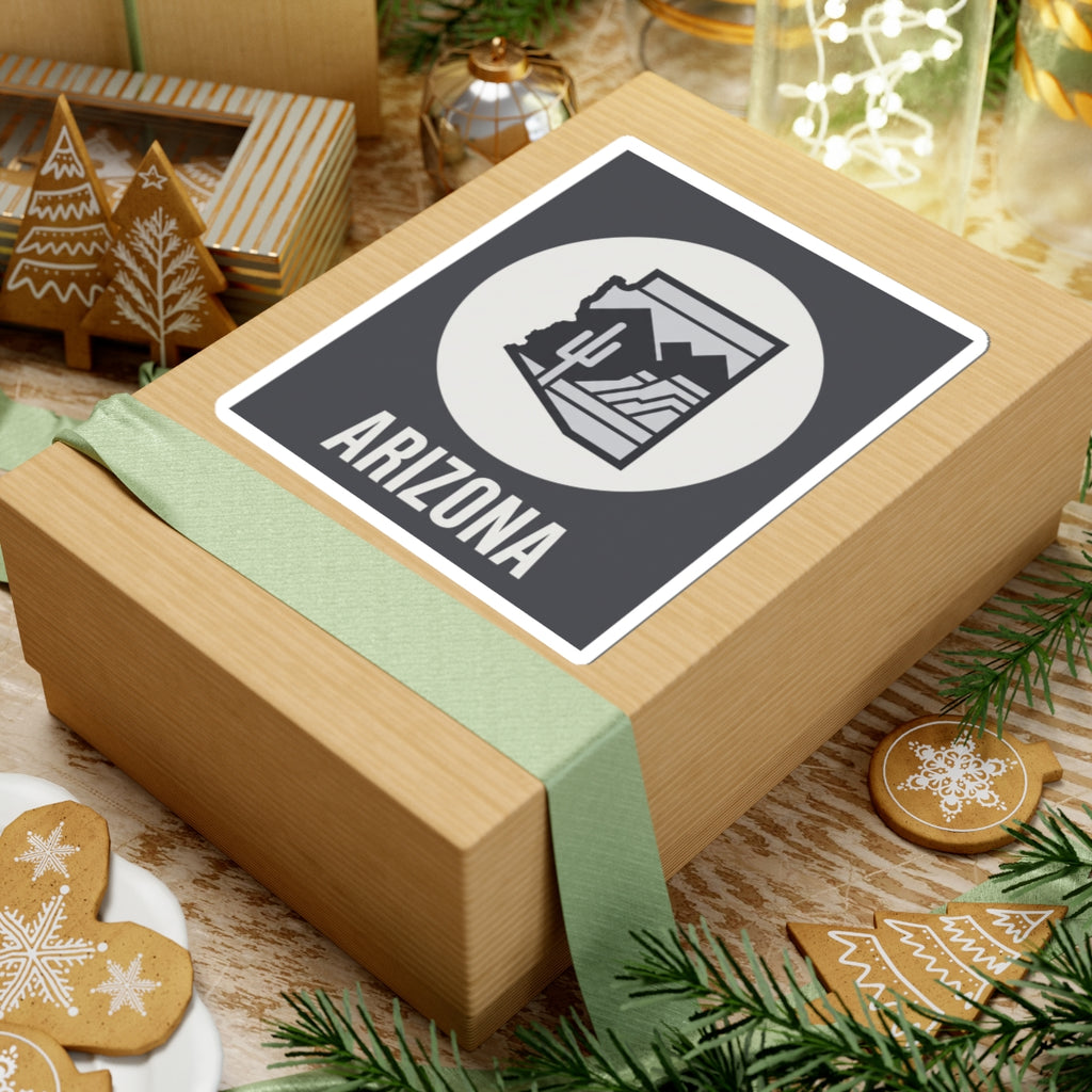 Arizona badge sticker on gift box: dark square with white circle desert graphic and ARIZONA text