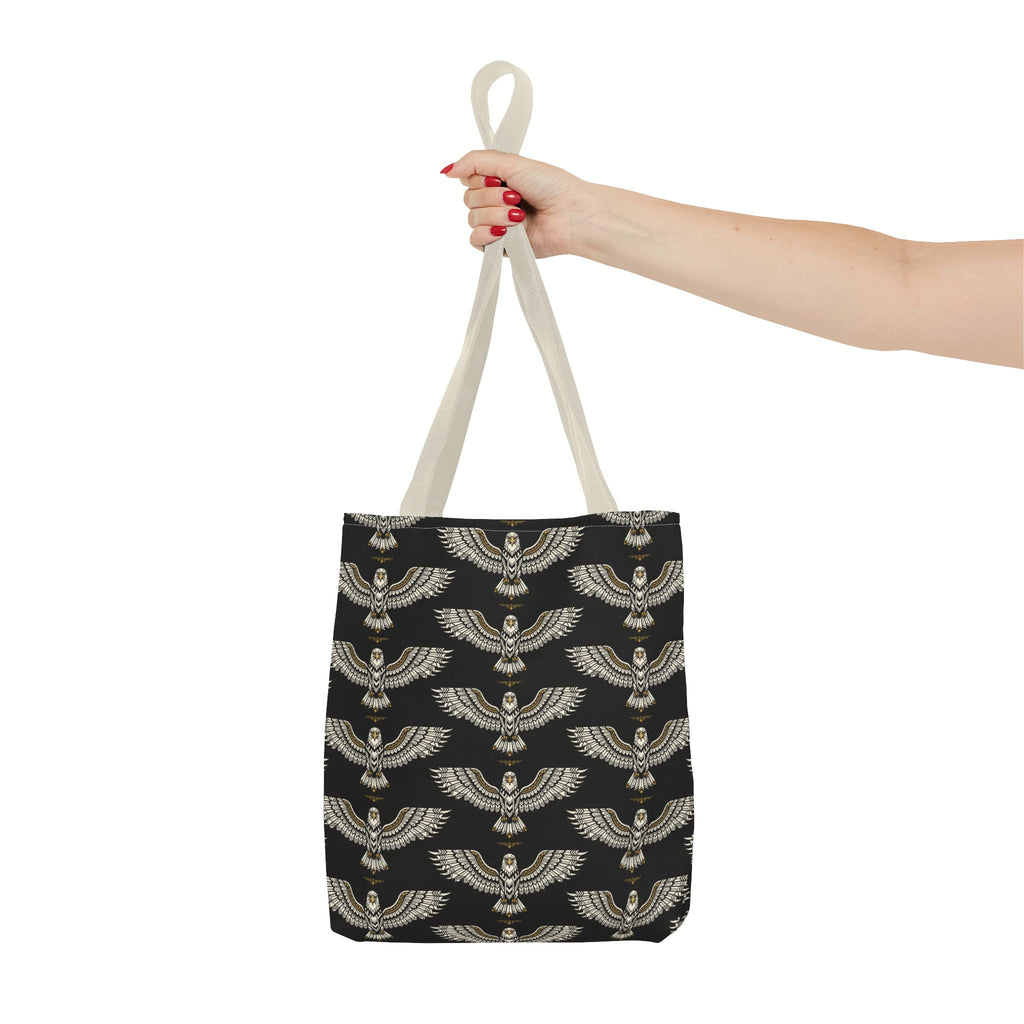 Winged scarab tote bag held by two hands, black body with gold repeating pattern