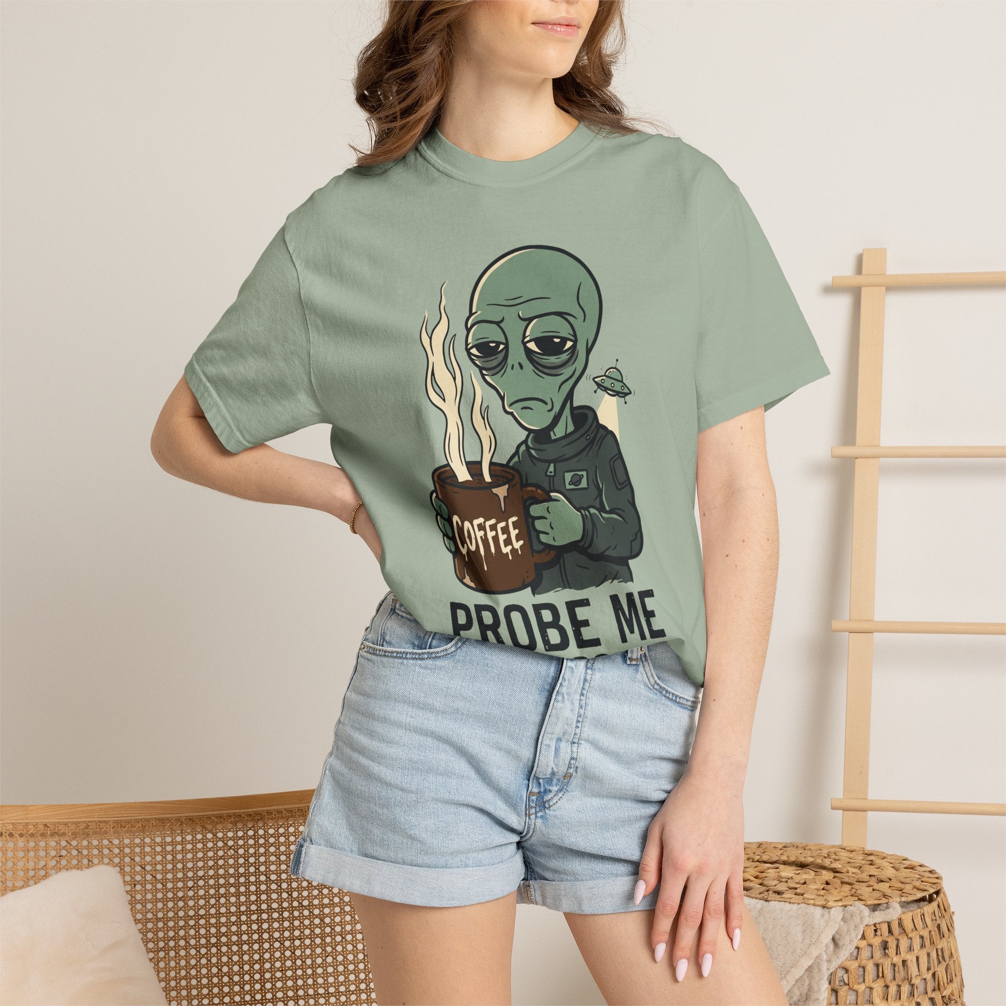 Sage green short-sleeve T-shirt with alien holding coffee and “PROBE ME” graphic on chest