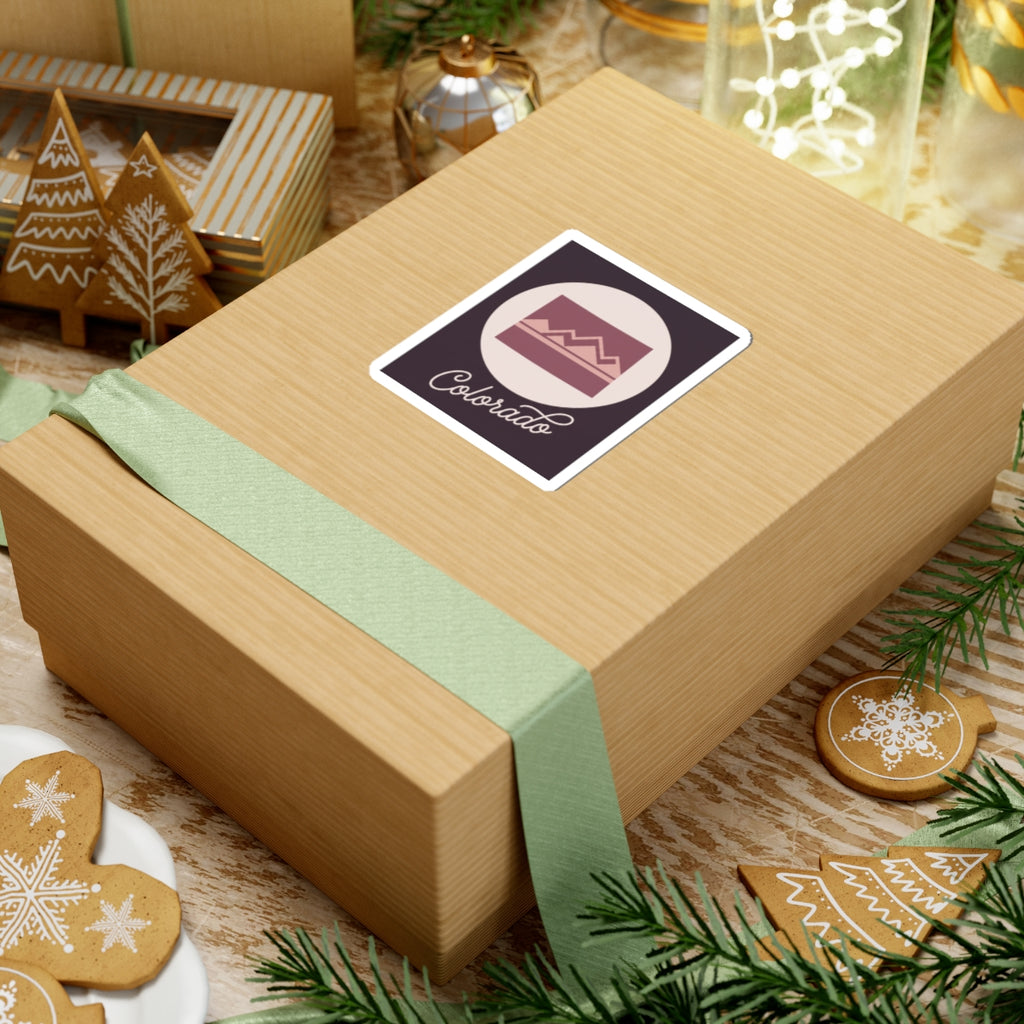 Colorado sticker on a wrapped gift box: mauve landscape graphic in white circle