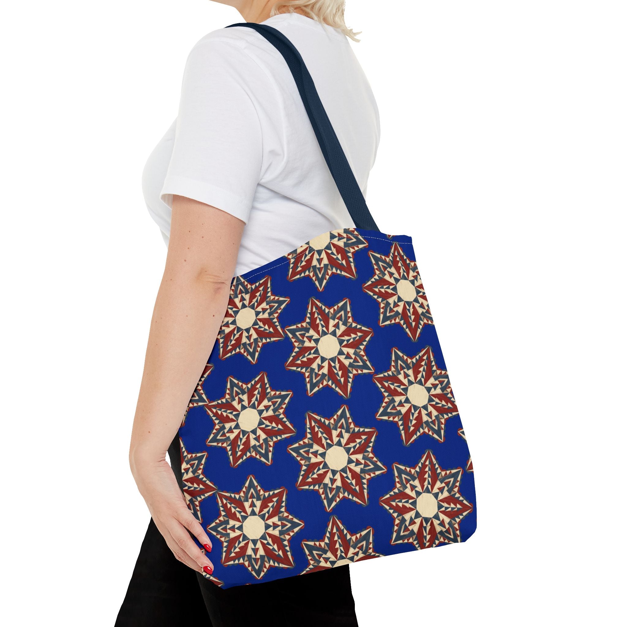 Blue tote bag with red and cream starburst floral print, shown from side while carried.