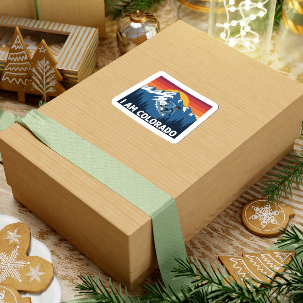 I Am Colorado sticker on gift box, snowboarder over mountains with pine trees and white outline
