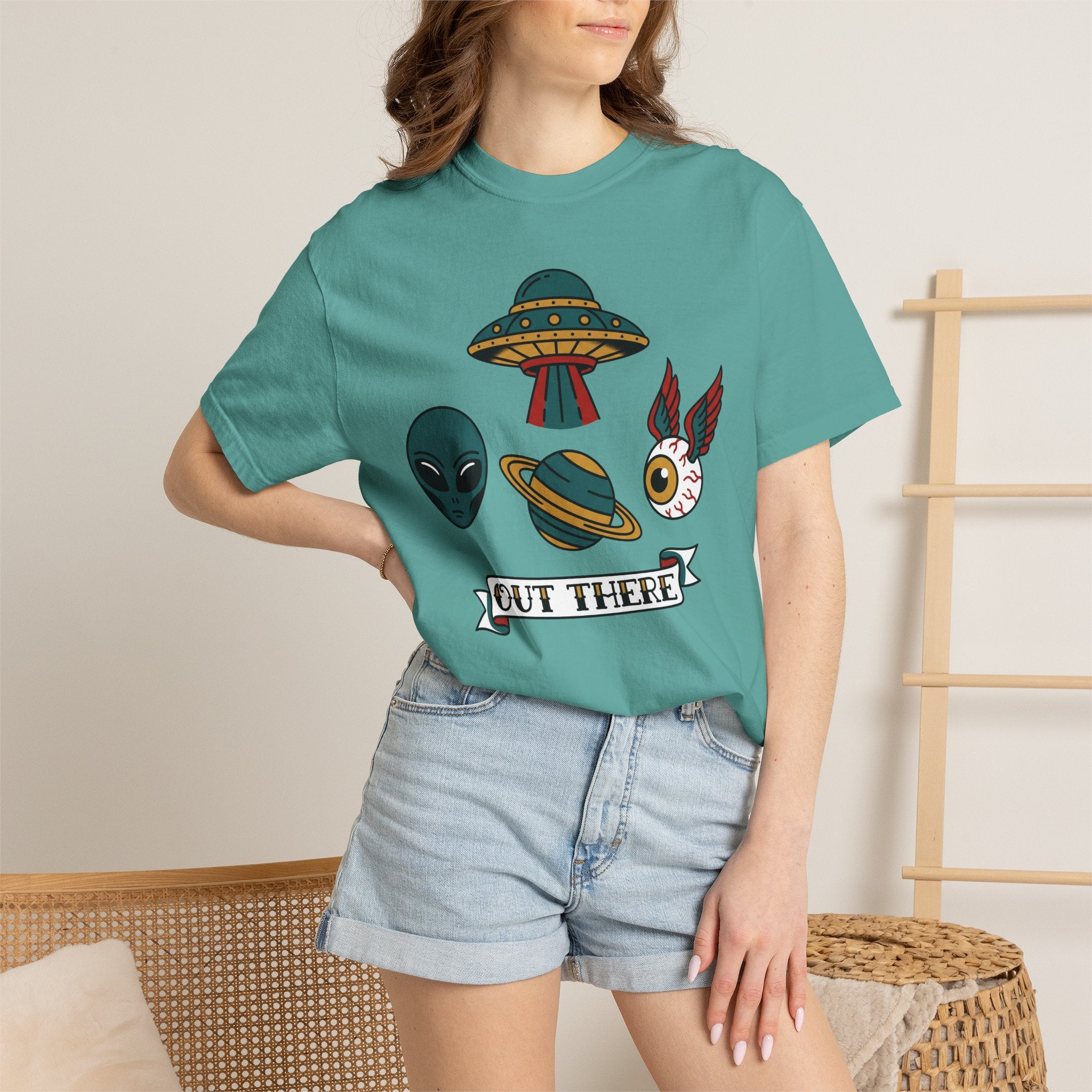 Teal crewneck T-shirt with UFO and alien patch graphic, worn with denim shorts.
