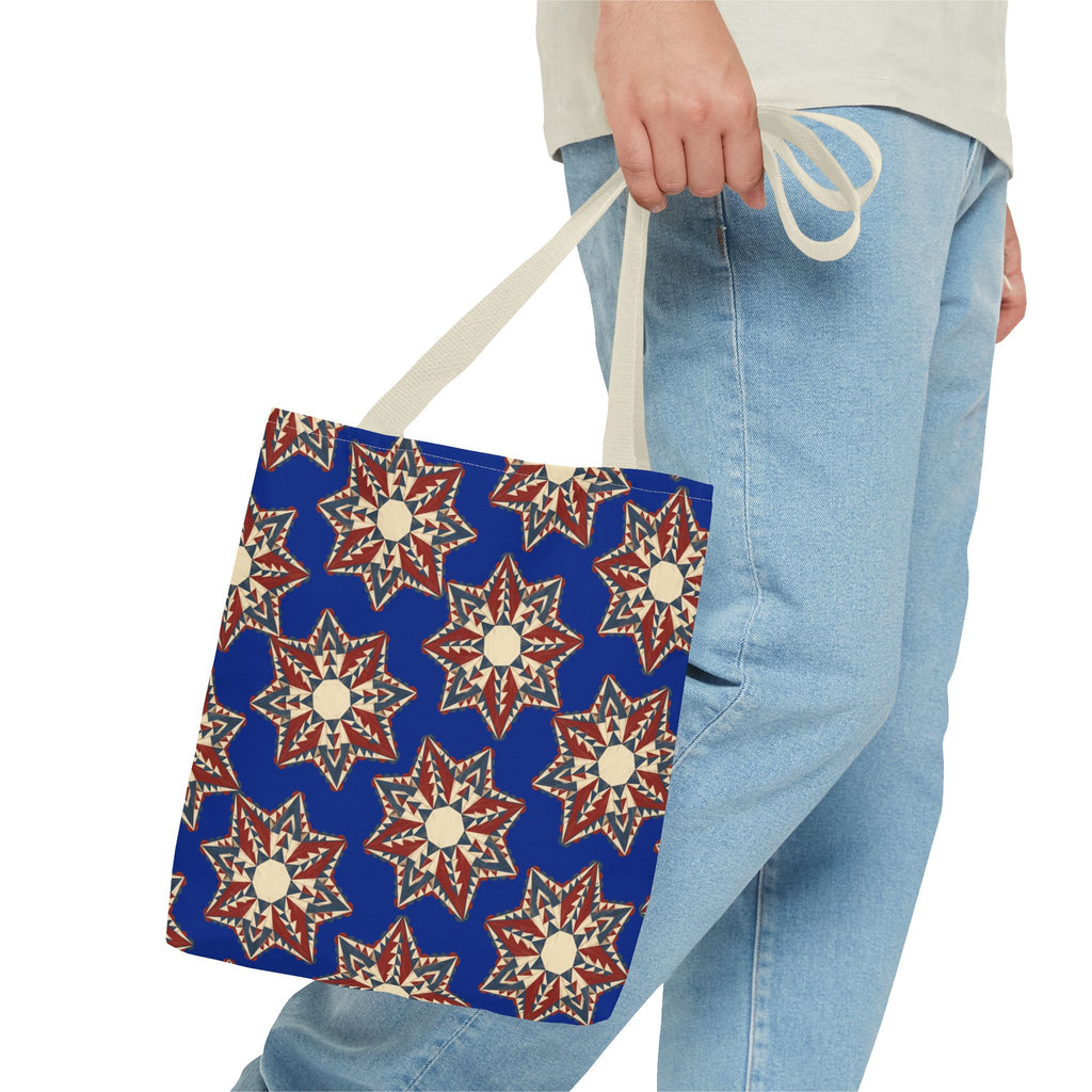 Blue tote bag with starburst floral pattern in cream and red, carried by light straps