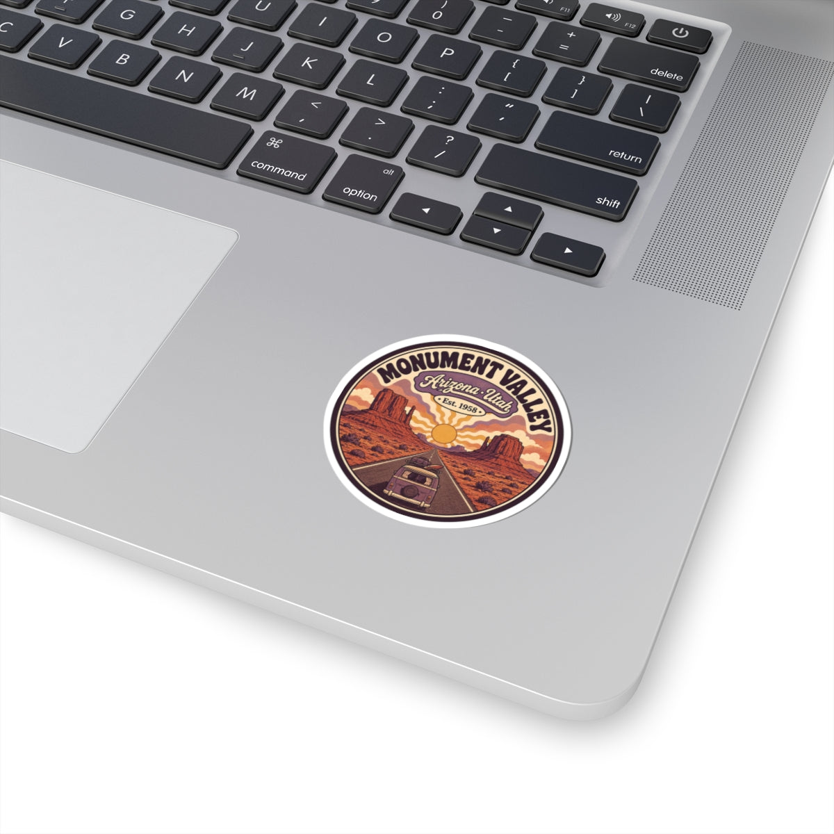 Round kiss-cut sticker with desert road, sunset sky, and Monument Valley text