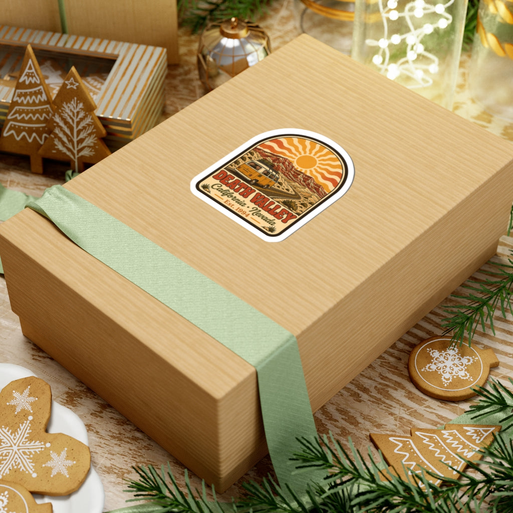 Arch-shaped sticker on gift wrap featuring yellow van, desert hills, and Death Valley label