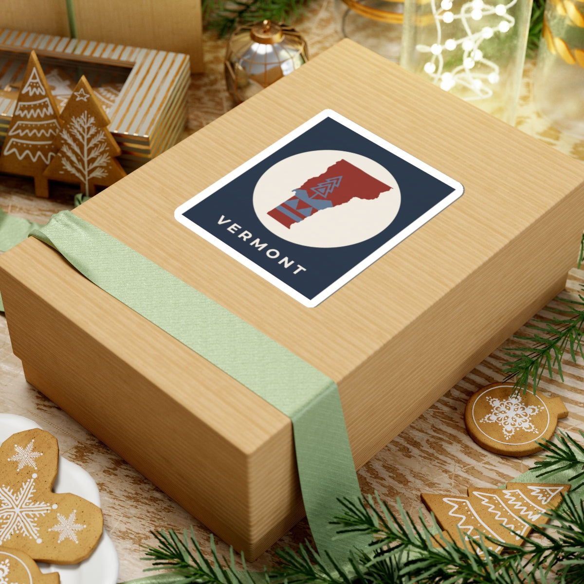 Vermont map sticker with navy border, beige oval, red state, blue geometric trees, 'VERMONT'