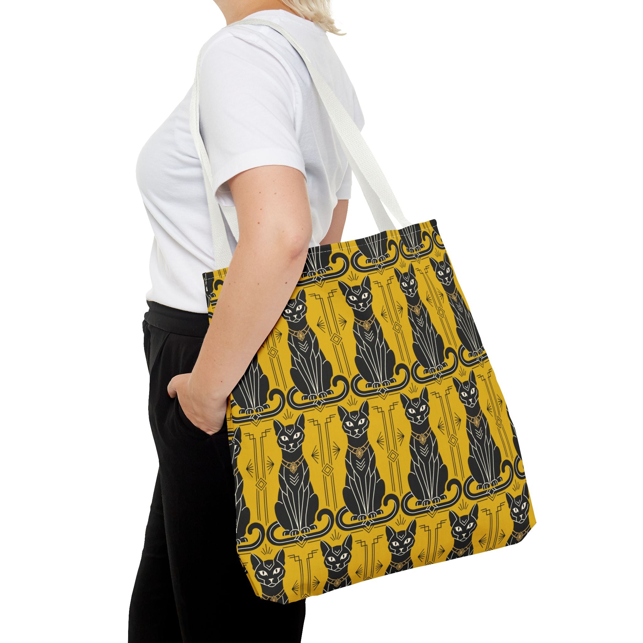 Yellow cat-pattern tote bag worn over shoulder, navy cat silhouettes and swirls