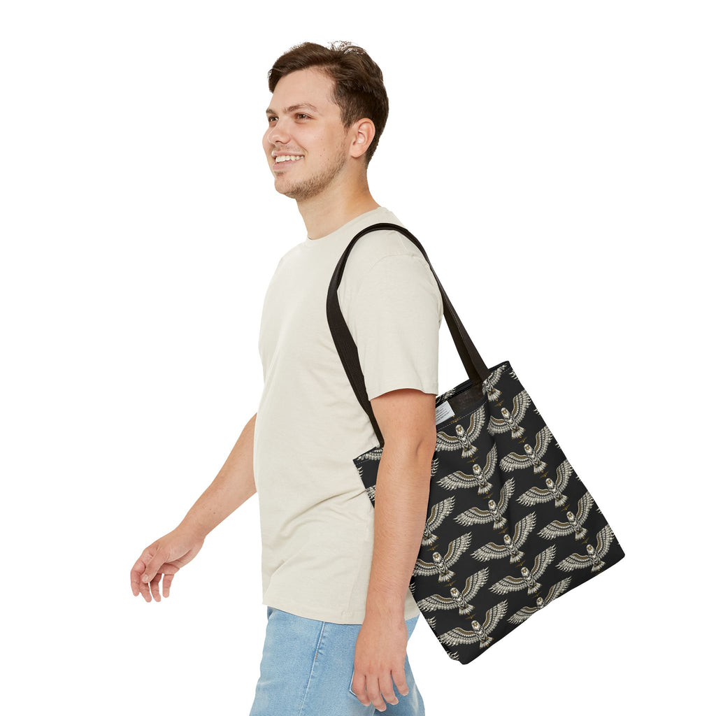 Black tote bag with gold winged scarab pattern, shown worn over shoulder
