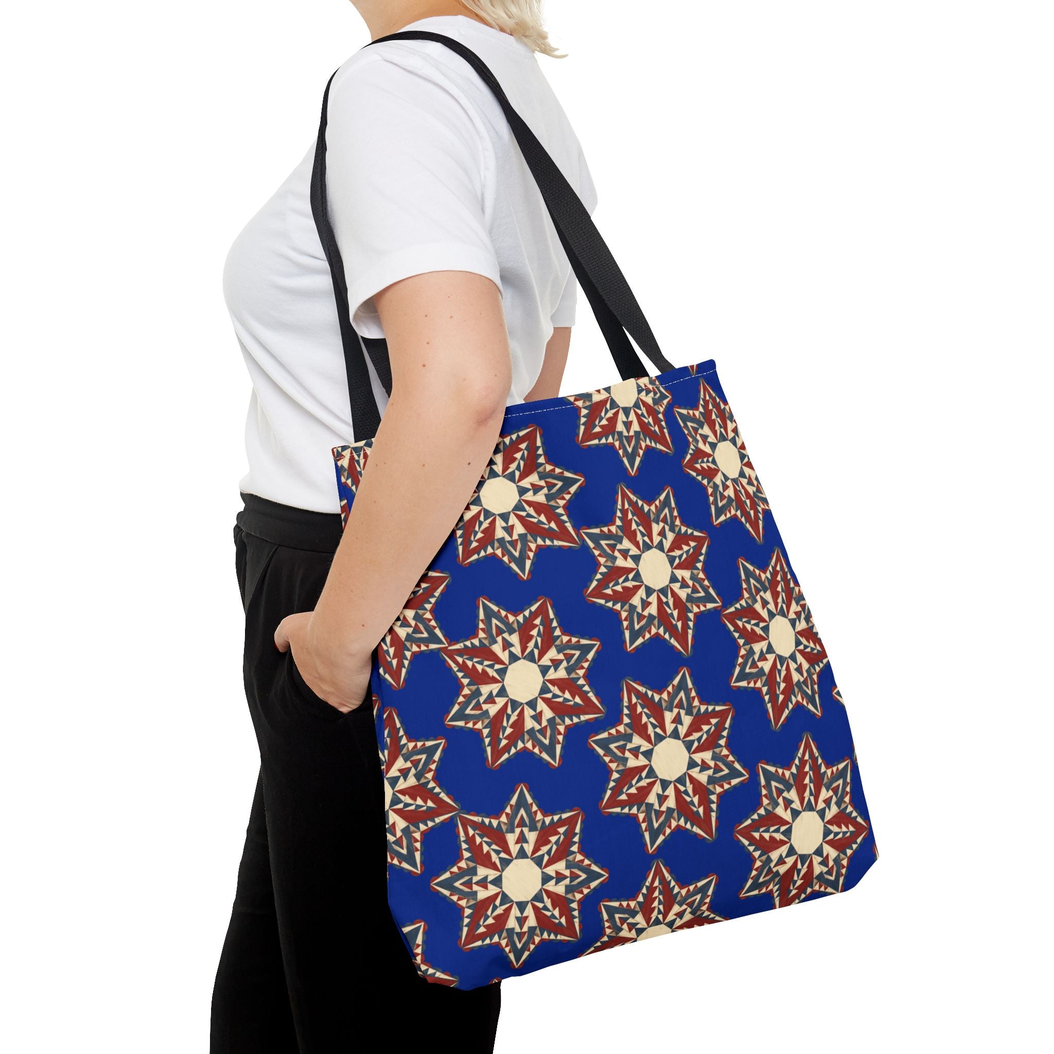 Blue tote bag with starburst floral pattern and black shoulder straps, side view