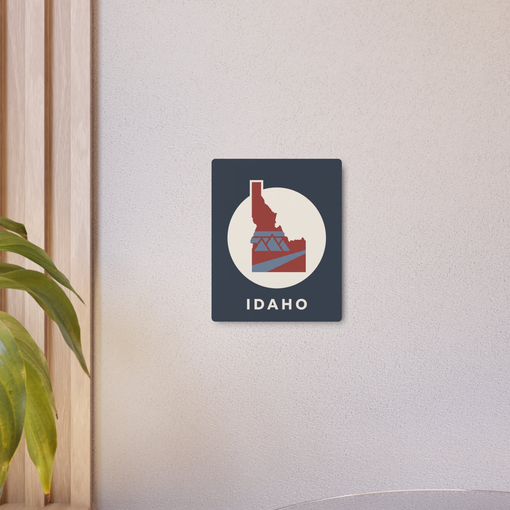 Idaho state metal sign, dark blue with circular graphic and IDAHO wordmark in white