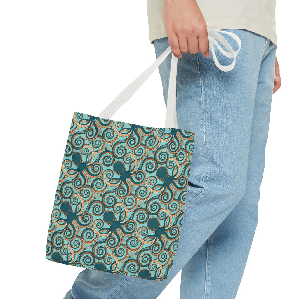 Octopus swirl tote bag held by top handle; teal all-over pattern with white strap.
