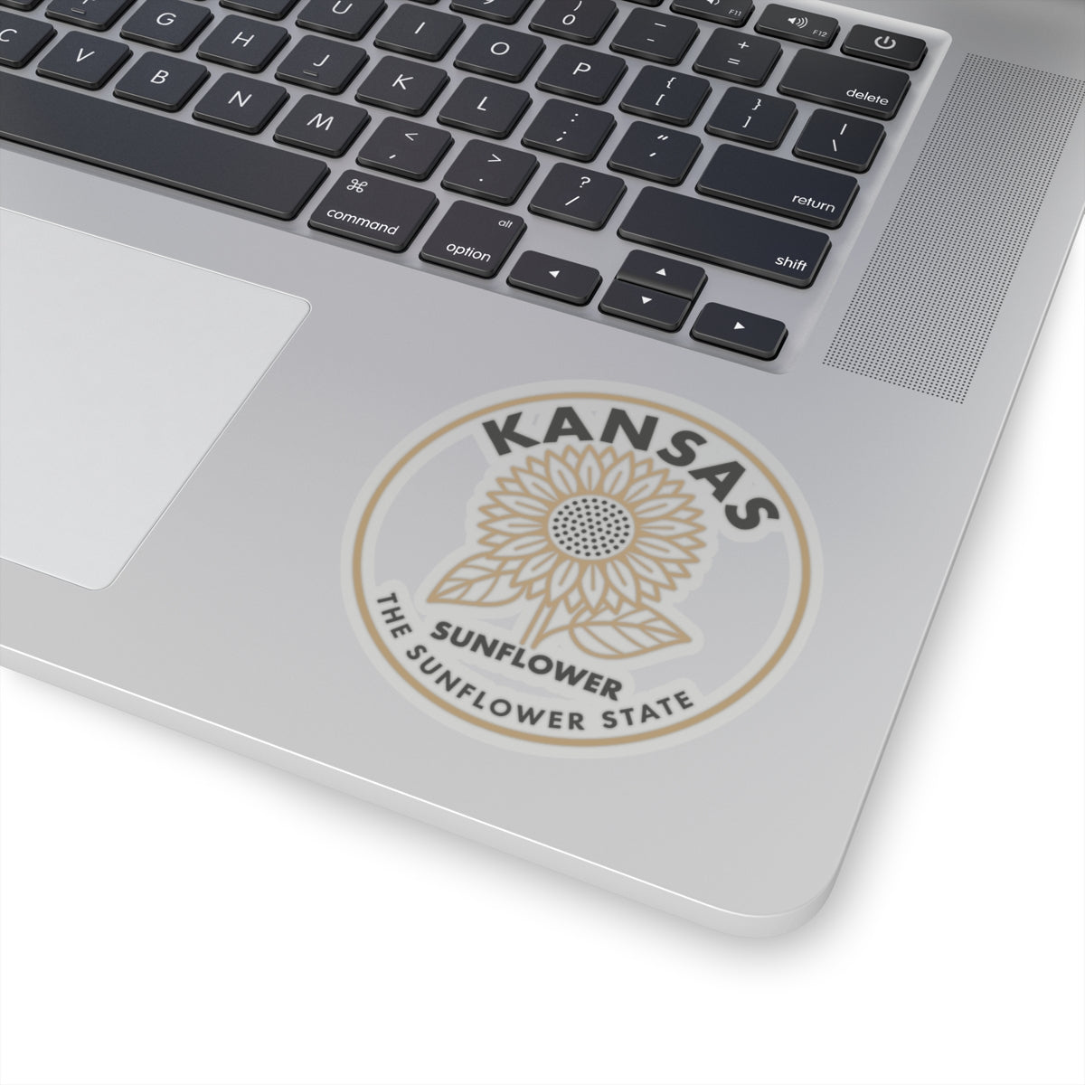 Round Kansas sunflower state decal centered on laptop lid, beige sunflower logo