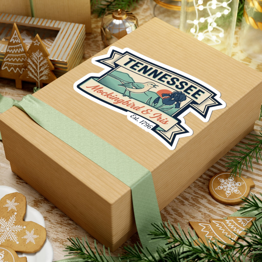 Tennessee vinyl sticker on a wrapped gift box showing bird, iris flowers, and badge