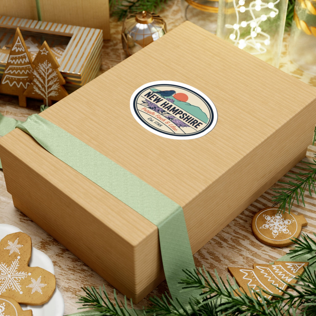 Round New Hampshire state badge sticker on a gift box with purple finch and lilac design