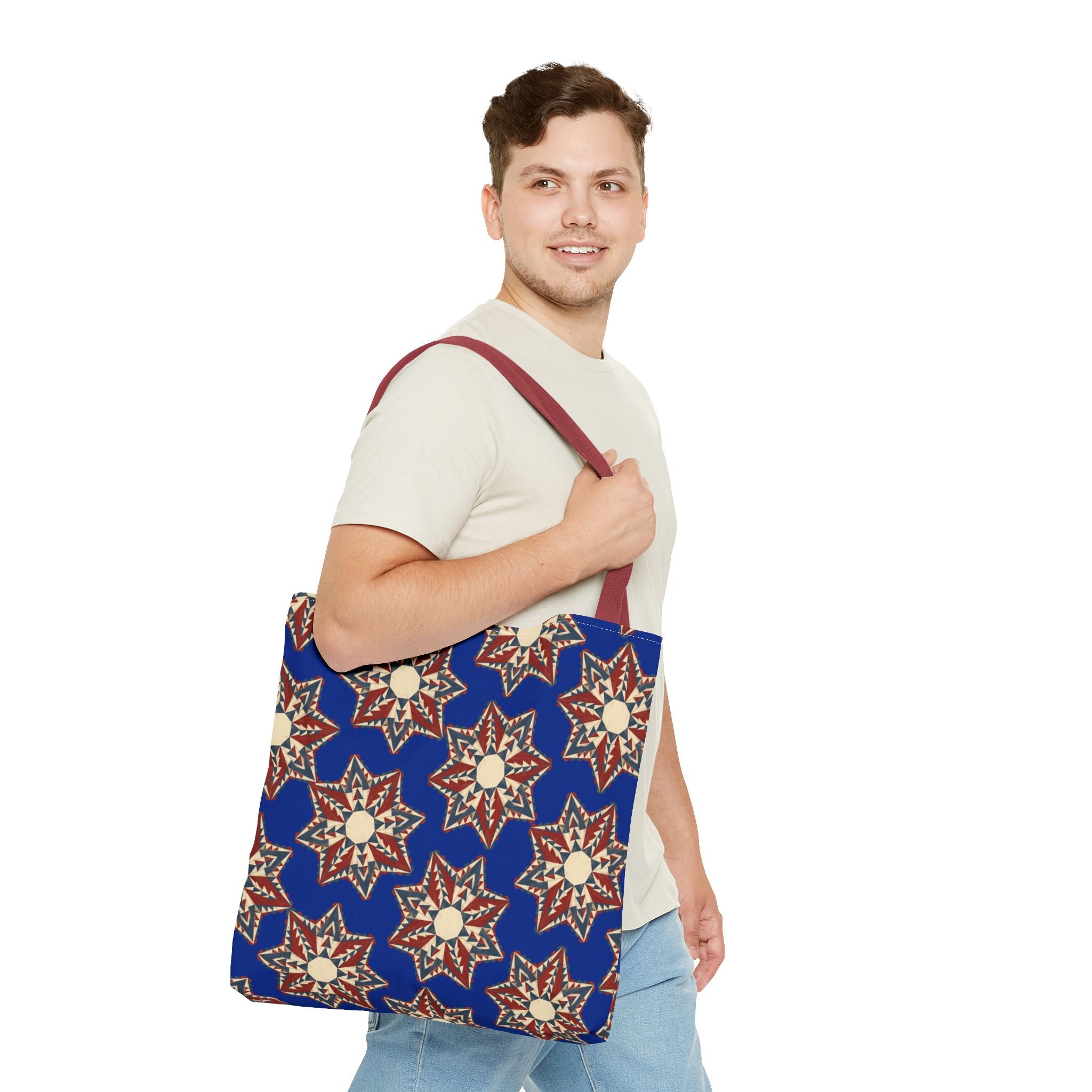Blue starburst floral tote bag with burgundy shoulder straps worn over a T-shirt